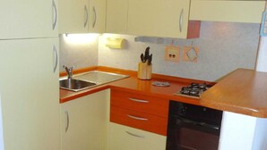 Une cuisine de taille réduite, équipée d’un évier, d’une cuisinière et de placards.