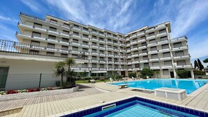 Un hôtel à plusieurs étages doté d’une piscine et d’un espace extérieur aménagé pour se détendre.