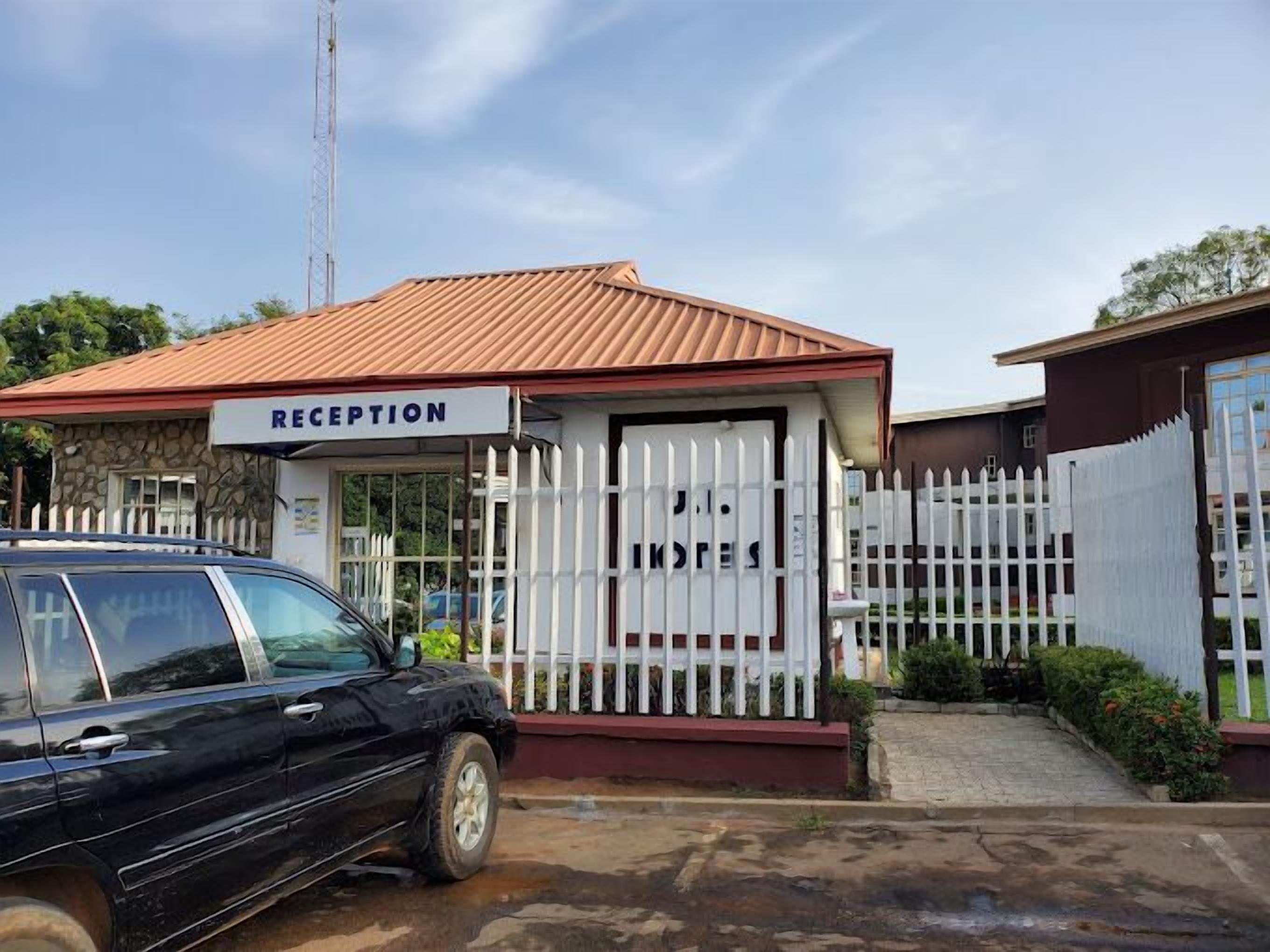 A reception area with a sign, a white fence, and a parked car.