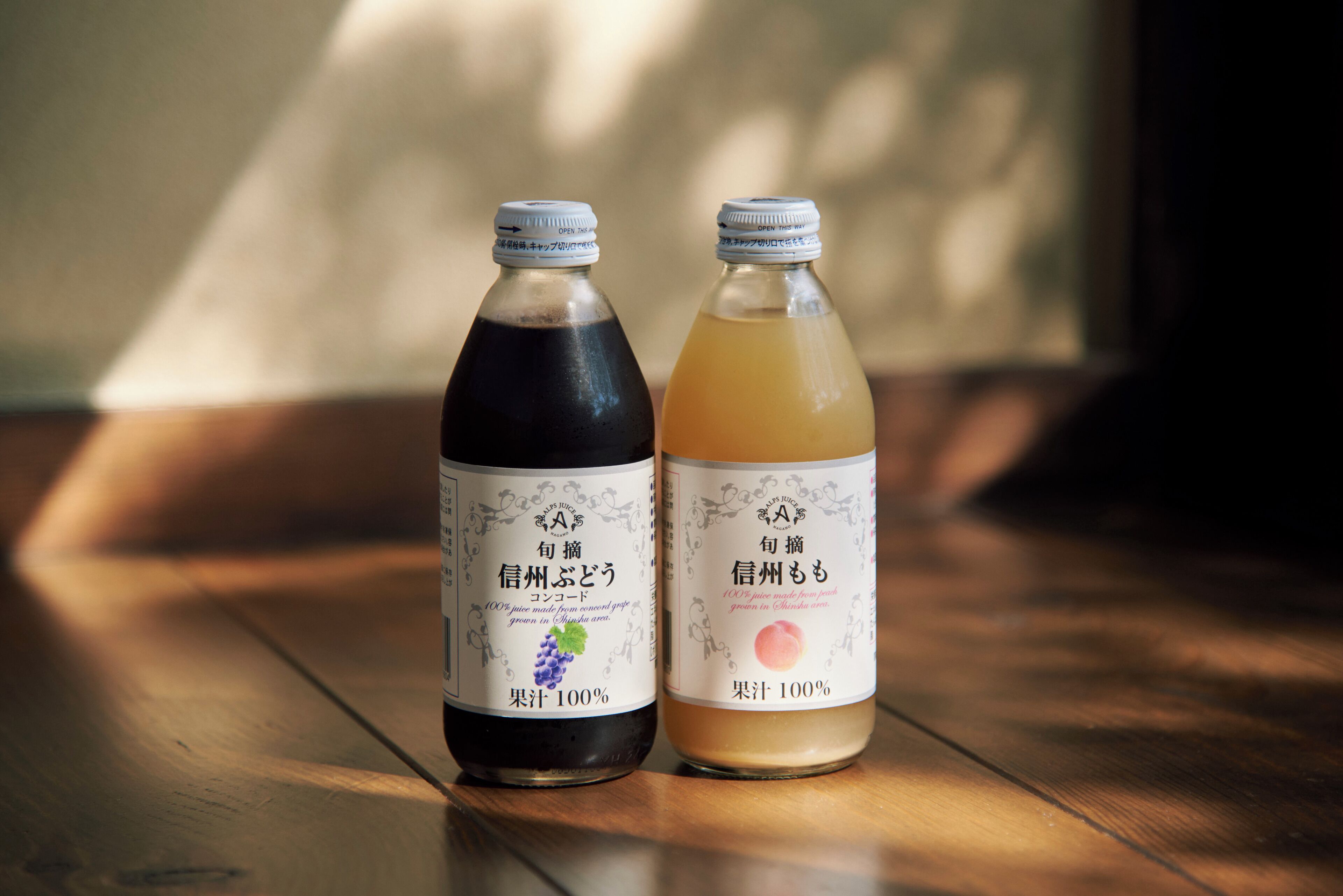 Two bottles of beverage on a wooden surface with a blurred background.