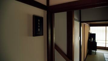 A traditional Japanese interior with tatami flooring, a shoji screen, and a dark wooden door.