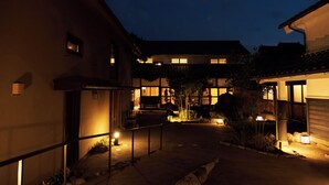 A courtyard with buildings, a bench, and a small tree. - Travel Stop UNNOWA (Tomi)