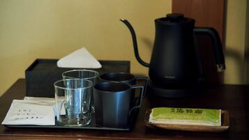 A tray with a tea set, including a teapot, cups, and a tray of green tea.