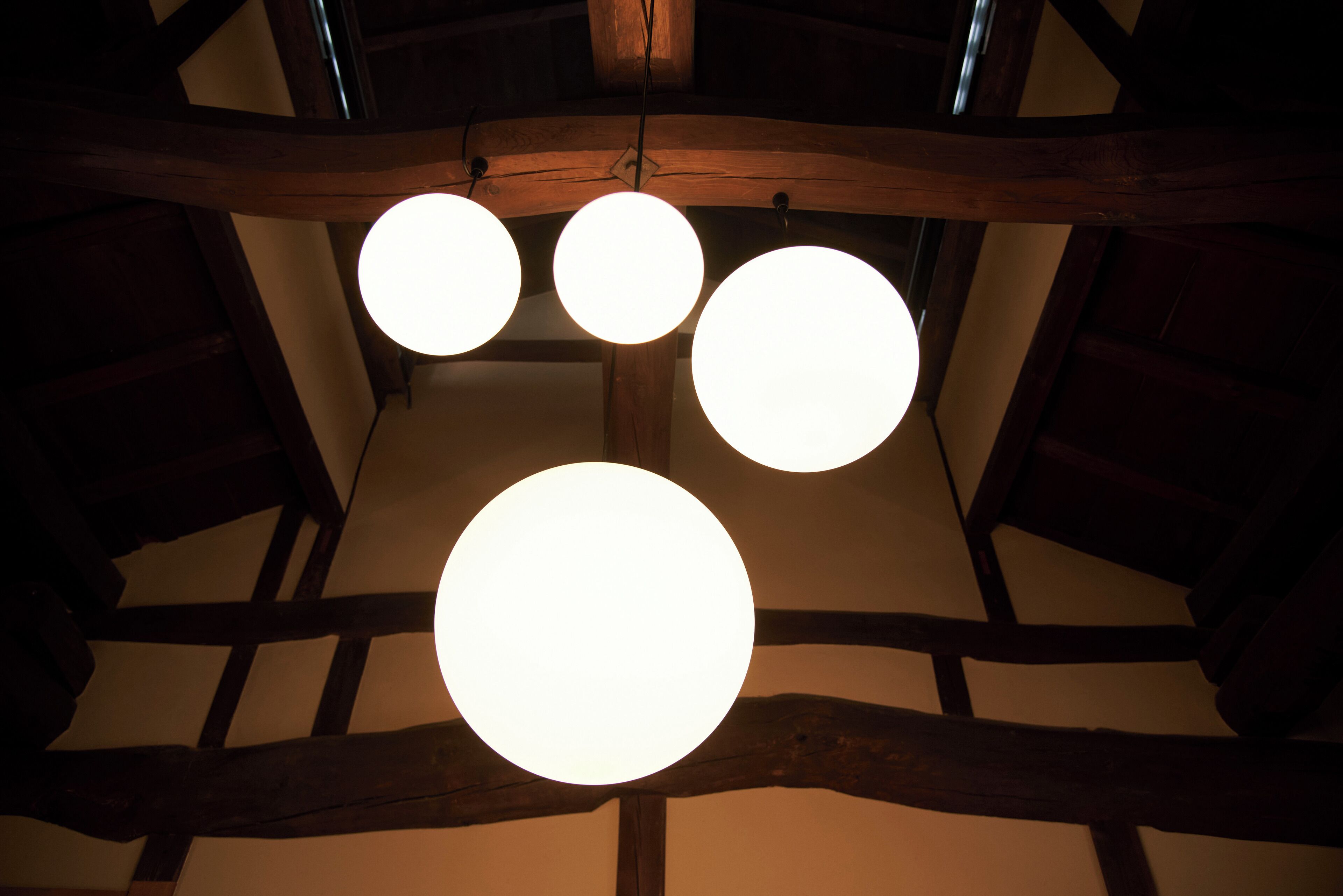 Eine Decke mit drei runden Leuchten und freiliegenden Holzbalken.