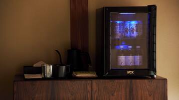 A wooden cabinet with a black HCK refrigerator displaying Japanese beverages.