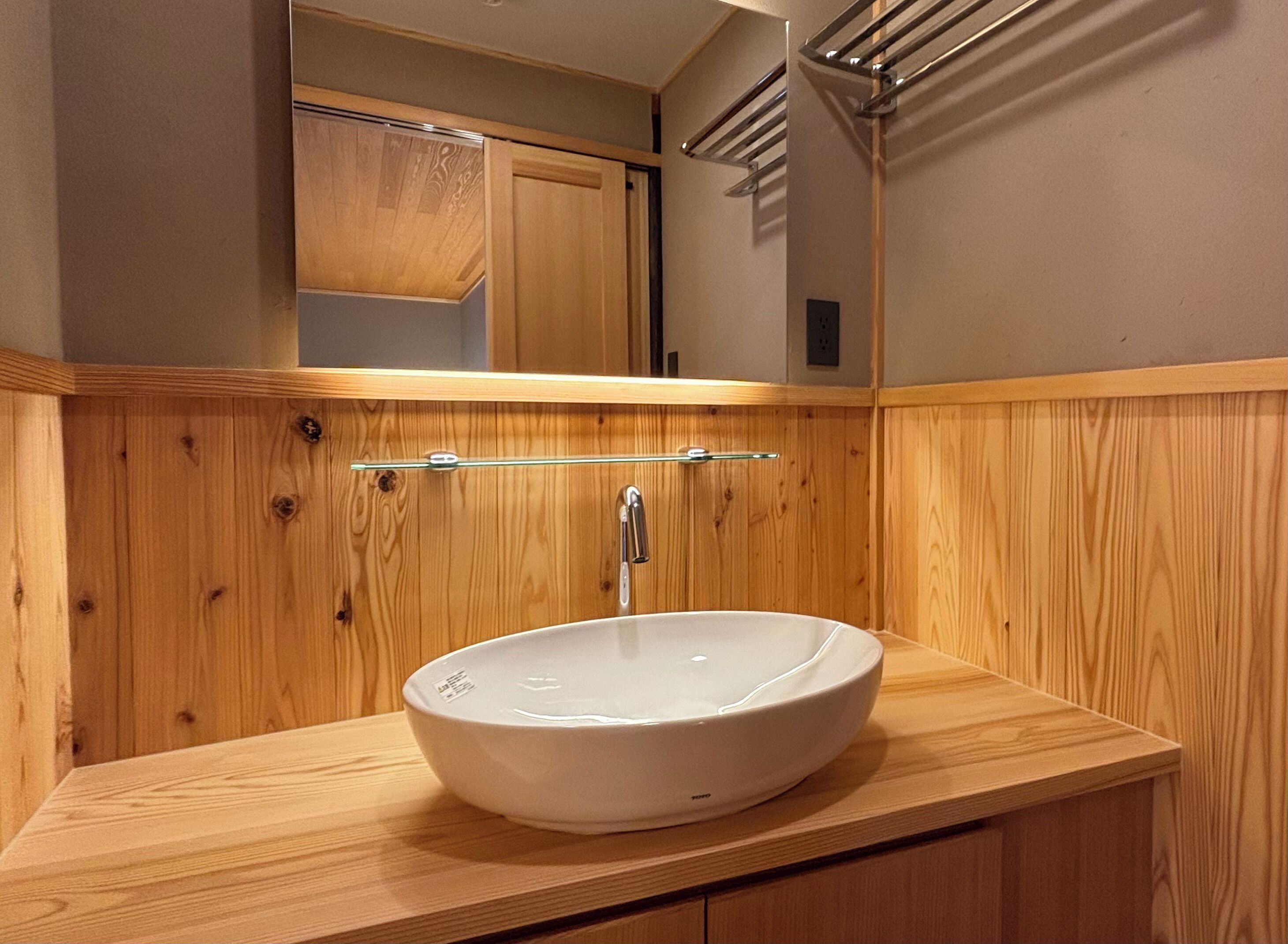 Une salle de bain avec un meuble-lavabo en bois, un lavabo blanc et un miroir au-dessus.