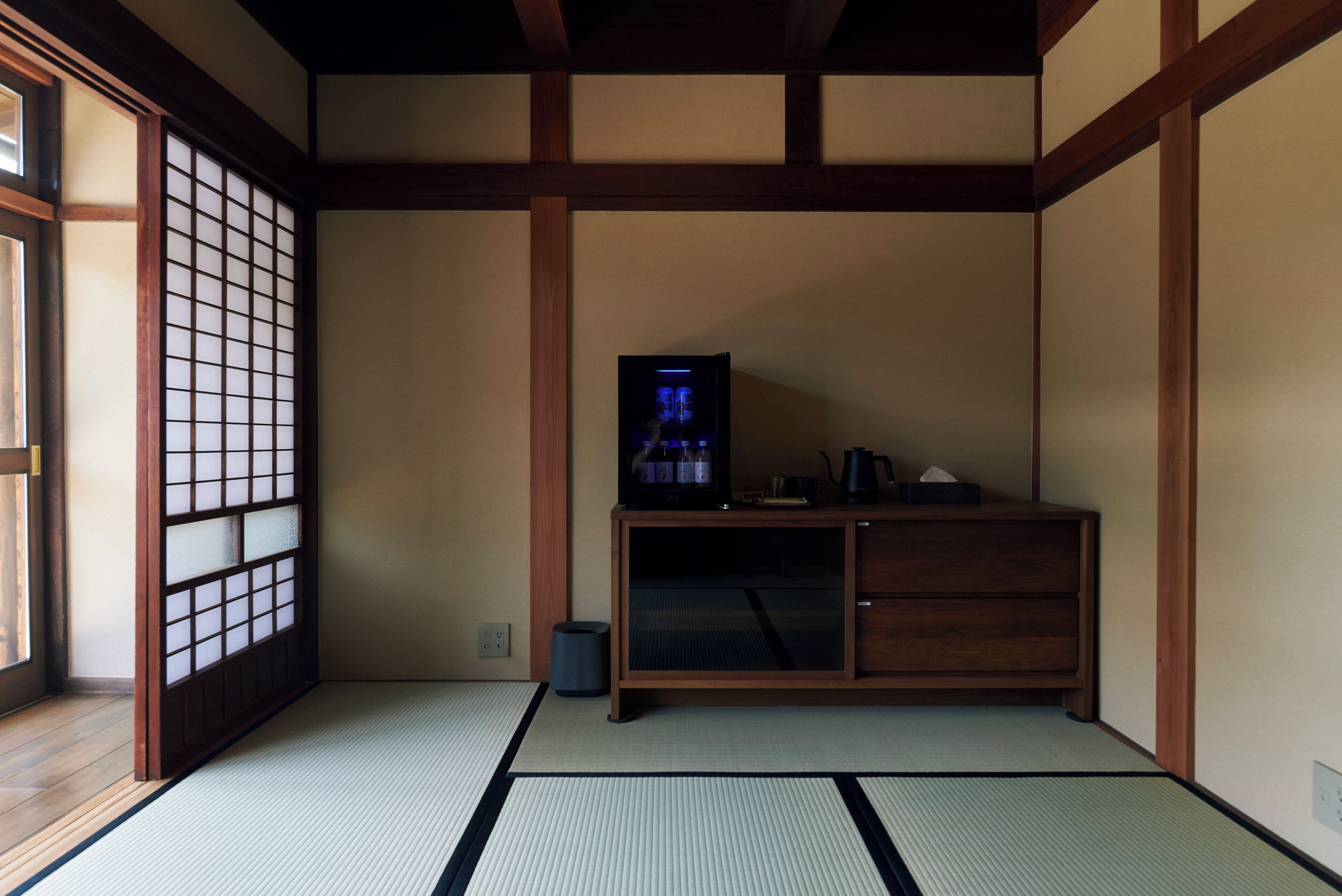 A traditional Japanese room with tatami flooring, a low wooden cabinet, and a television.