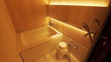 A small bathroom with a bathtub, toilet, and shower.