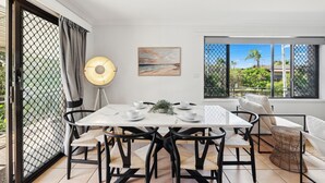 Un comedor moderno con una mesa blanca, sillas negras y una lámpara de pie.