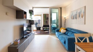 A modern living room with a flat-screen TV, a blue sofa, and a dining table.