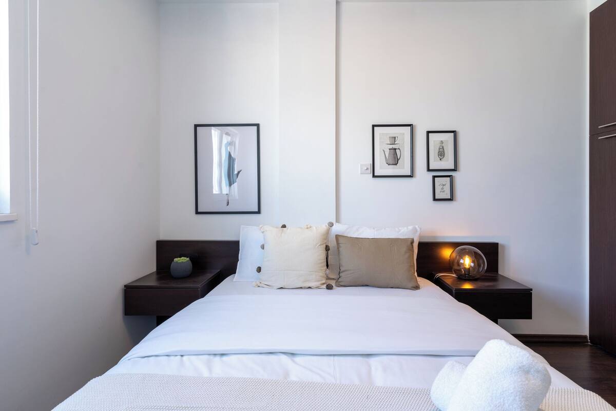 A modern bedroom with a large bed, two bedside tables, and three framed pictures on the wall.