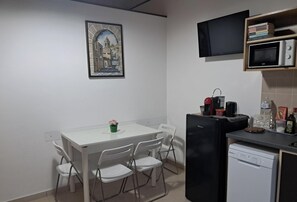 A compact kitchen with a white table, chairs, a black refrigerator, a microwave, and a dishwasher.