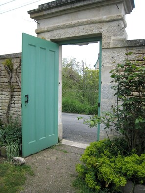 Una puerta verde que da a un edificio de piedra con un pequeño jardín.