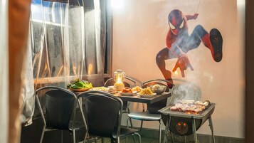 Comedor con una mesa lista para dos, una parrilla con carne, ensalada y un farol.