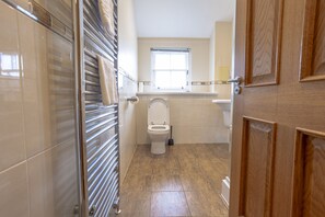 Un baño con inodoro, ventana y toallero.