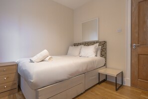 A bedroom with a bed, bedside table, and a wooden door.