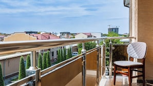 A balcony with a view of the cityscape, a chair, and a railing. - Sato Tashkent (Tashkent)