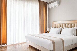 A hotel room with a bed, a nightstand, a lamp, and an air conditioning unit.