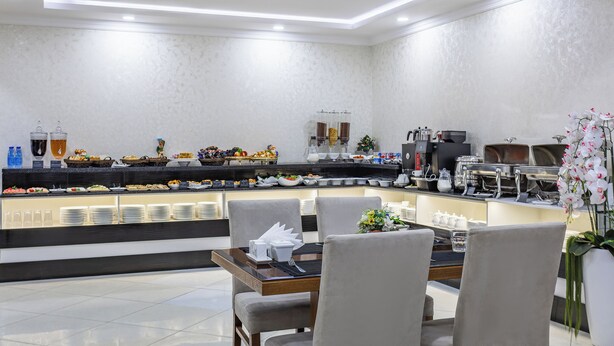 A modern breakfast bar with a variety of food options, a coffee station, and a seating area with chairs and a table. - Sato Tashkent (Tashkent)