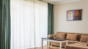 A modern living room with a wooden floor, a brown sofa, a coffee table, and a painting on the wall. - Sato Tashkent (Tashkent)