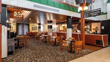 Un hall d’hôtel avec un sol carrelé en pierre, des meubles en bois et un panneau indiquant l’emplacement du garde-manger pour les clients.