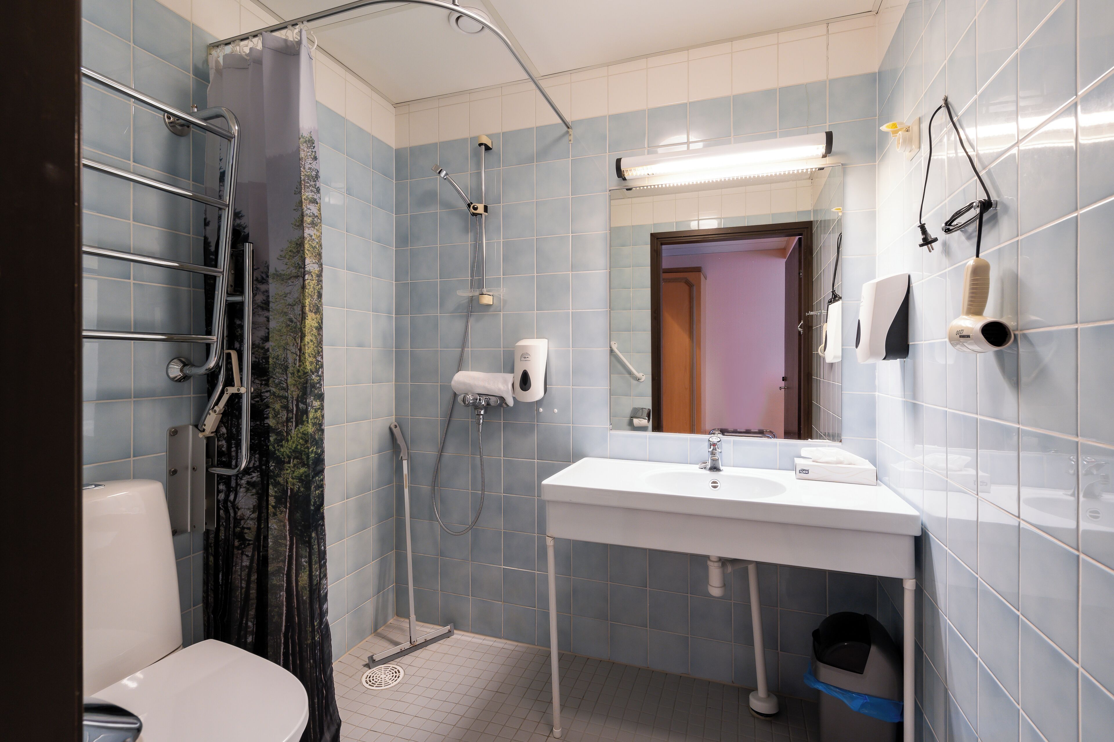 Ein Badezimmer mit Dusche, Toilette, Waschbecken und Handtrockner.