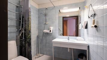 Ein Badezimmer mit Dusche, Toilette, Waschbecken und Handtrockner.
