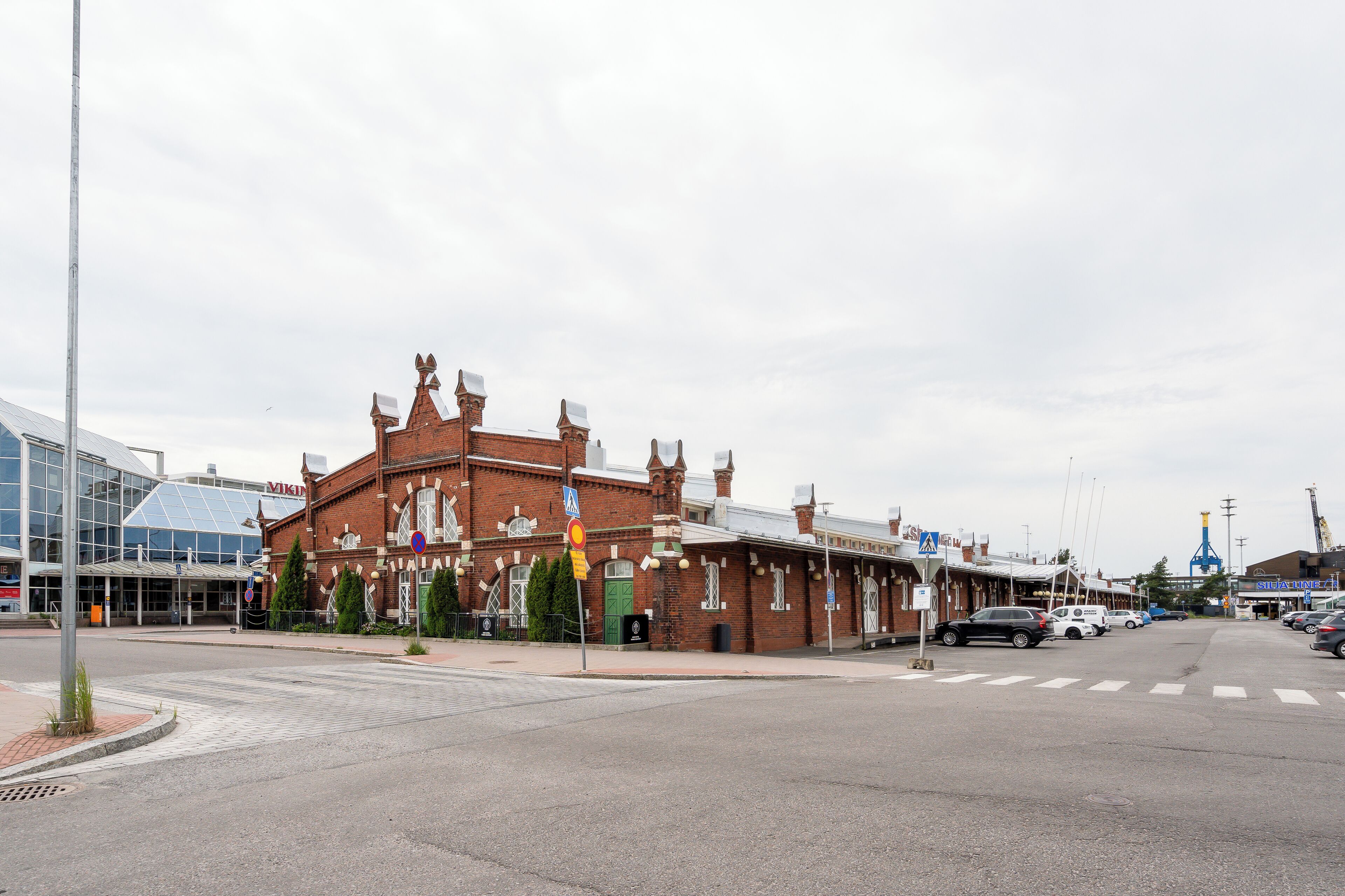 A historic building with a brick facade and multiple chimneys, adjacent to a modern glass structure.