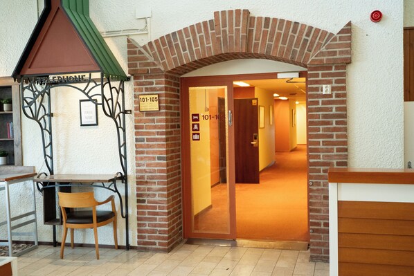 Un área de recepción con un arco de ladrillo, un escritorio de madera y una silla.