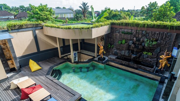 Una piscina sul tetto con un pontile in legno, poltrone da relax e due statue.