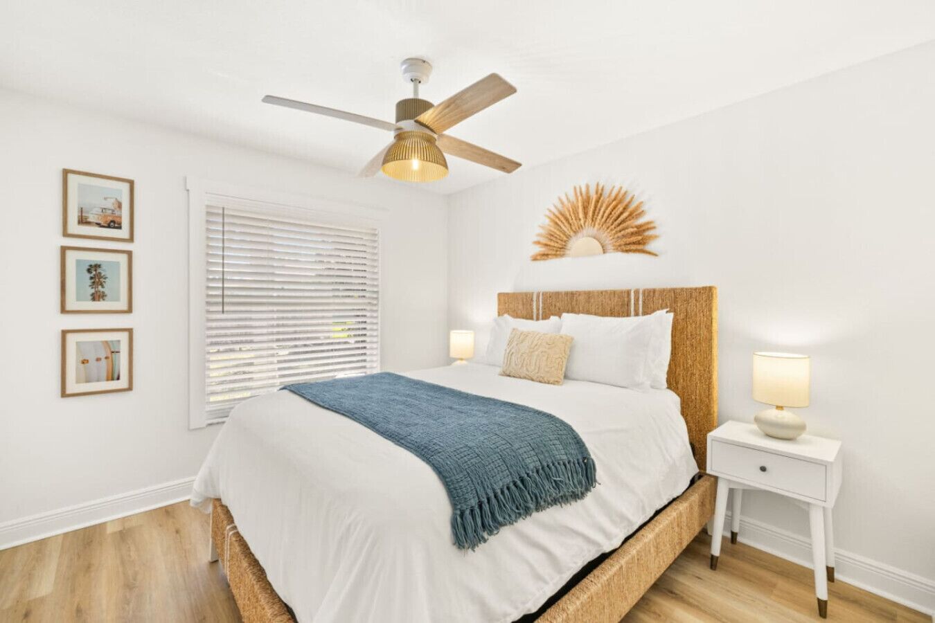A bedroom with a bed, a ceiling fan, a bedside table with a lamp, and a wall-mounted decorative piece.