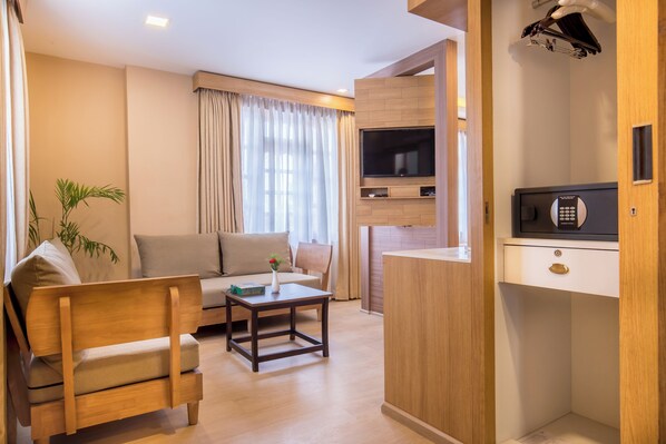 Un espacio habitable compacto con sofá, una mesita, televisión y microondas.