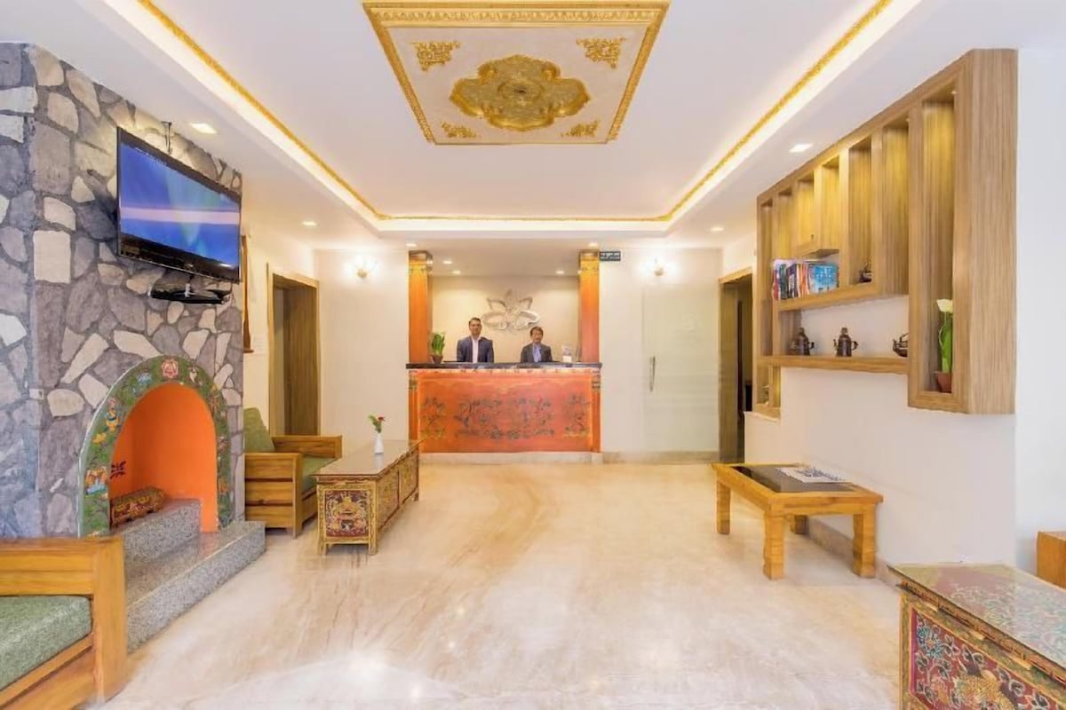 Un hall de hotel con chimenea de piedra, una recepción y un televisor en la pared.