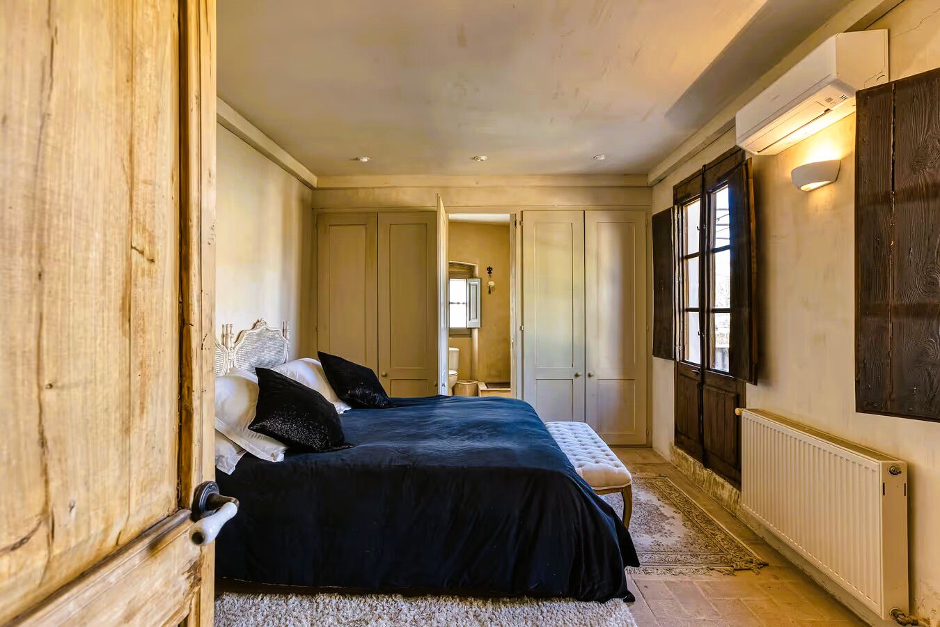 A bedroom with a large bed, wooden wardrobe, and a radiator.