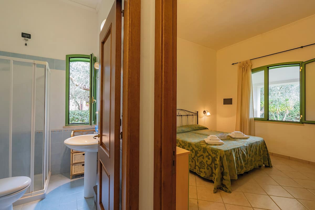 Une chambre à coucher avec un lit, une fenêtre et une salle de bain comprenant un lavabo et des toilettes.