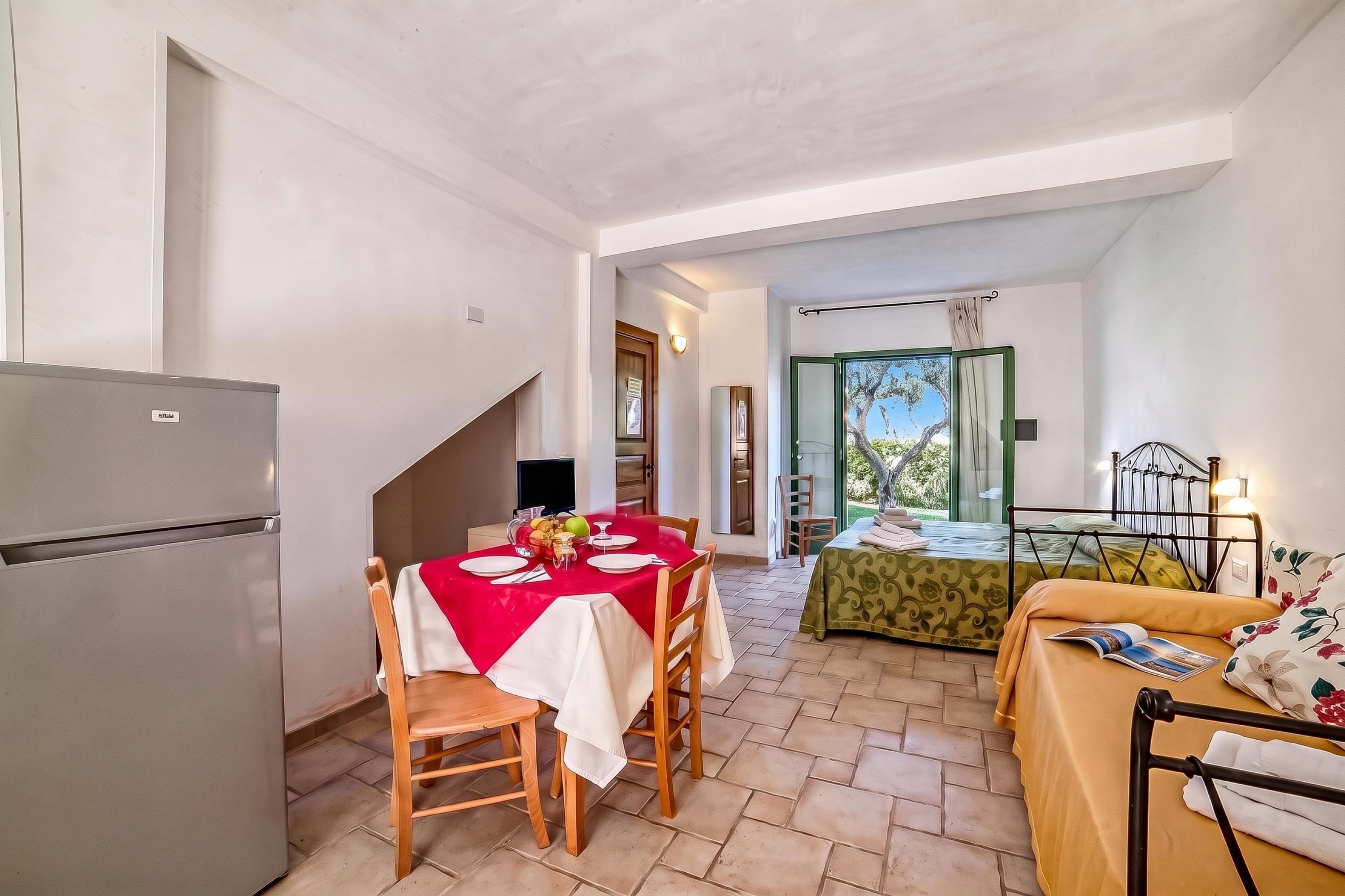 A compact living space with a dining area, a bed, and a kitchenette.