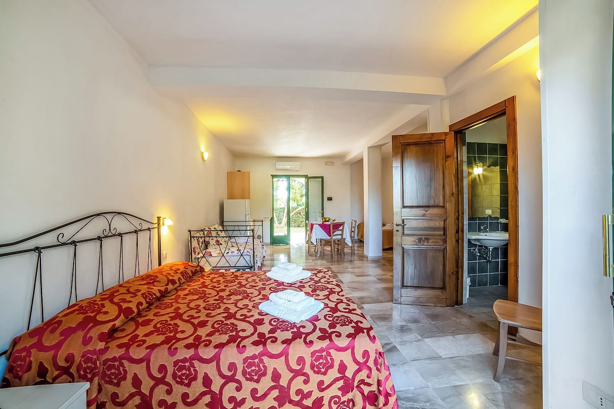 Une chambre d’hôtel comprenant un lit, un bureau, une chaise, une salle de bain et un coin repas.