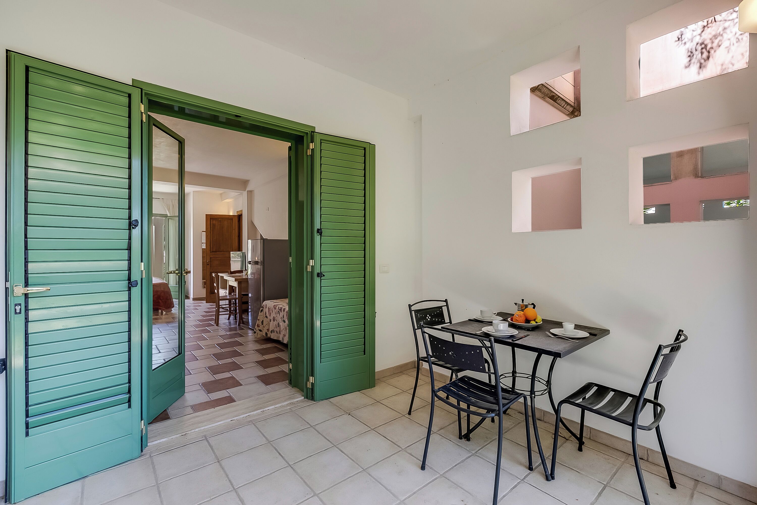 Una sala da pranzo con tavolo e sedie, una porta verde e un corridoio che conduce a un'altra stanza.