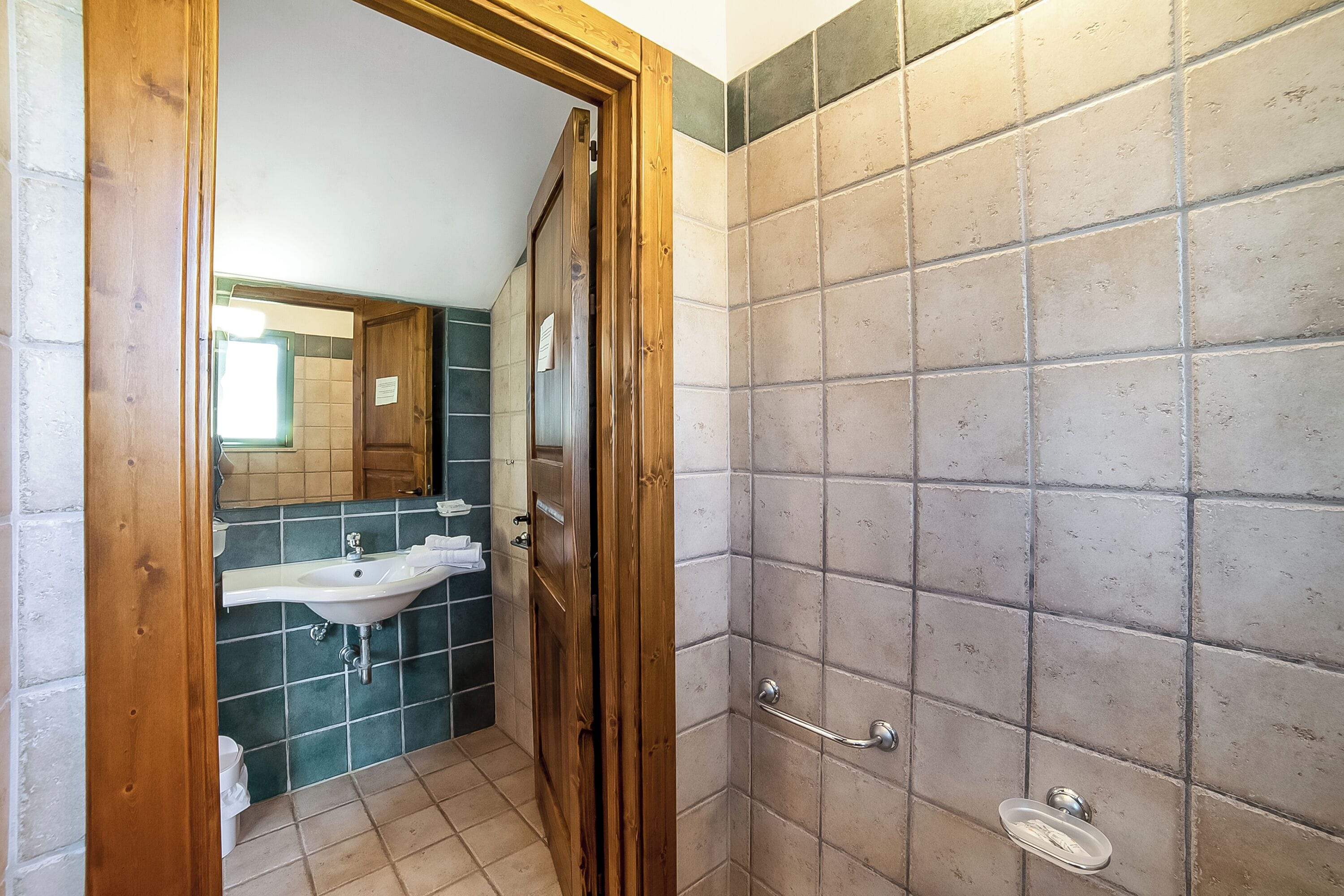 Une salle de bain avec une porte en bois, un lavabo et une douche carrelée.