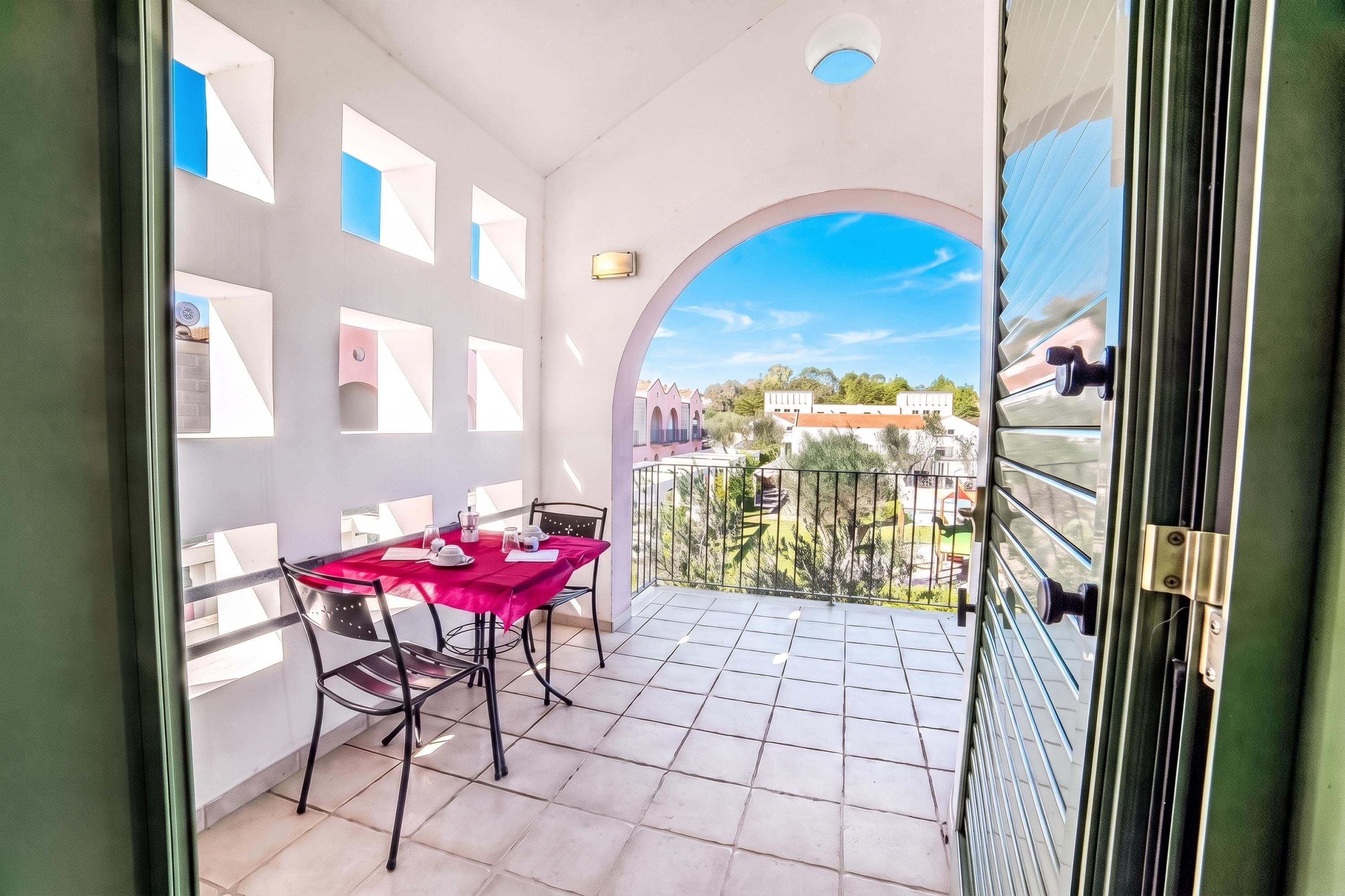 En balkon med et bord dækket til to, udsigt over de omkringliggende bygninger og en klar himmel.