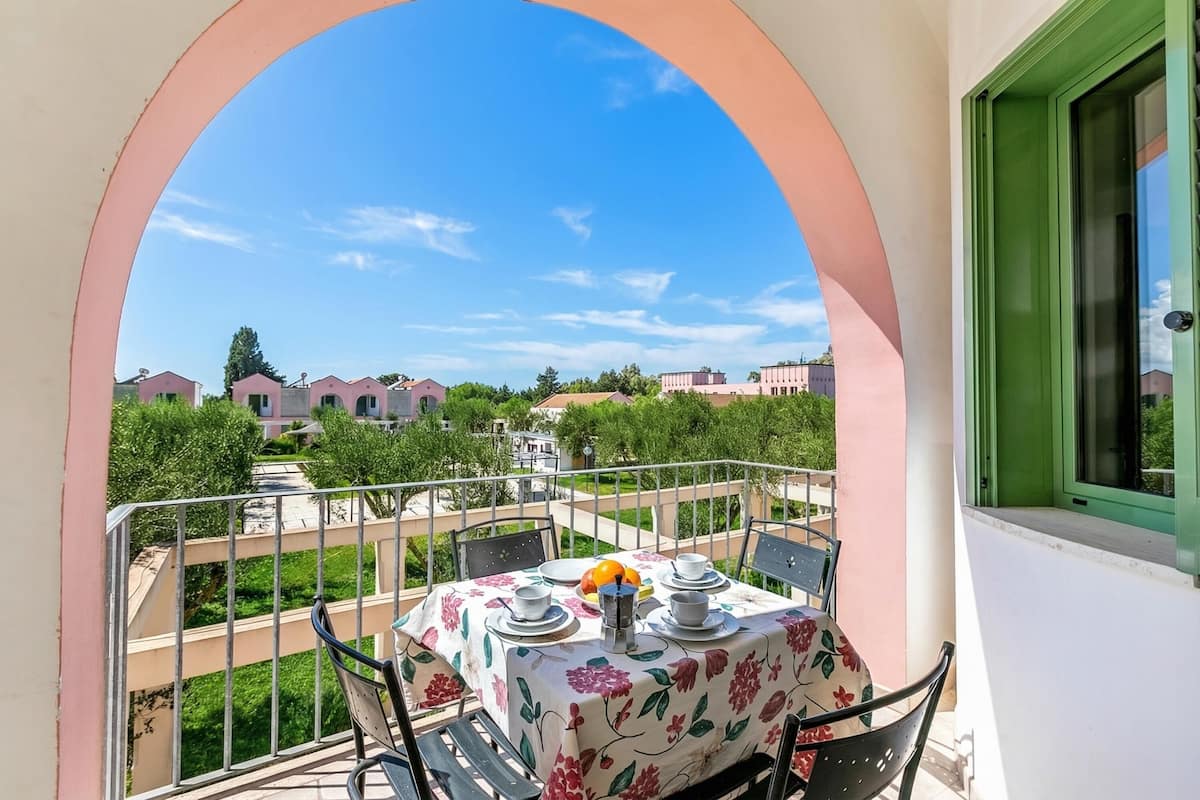 Un balcon avec une table dressée pour deux personnes, donnant sur un quartier résidentiel.