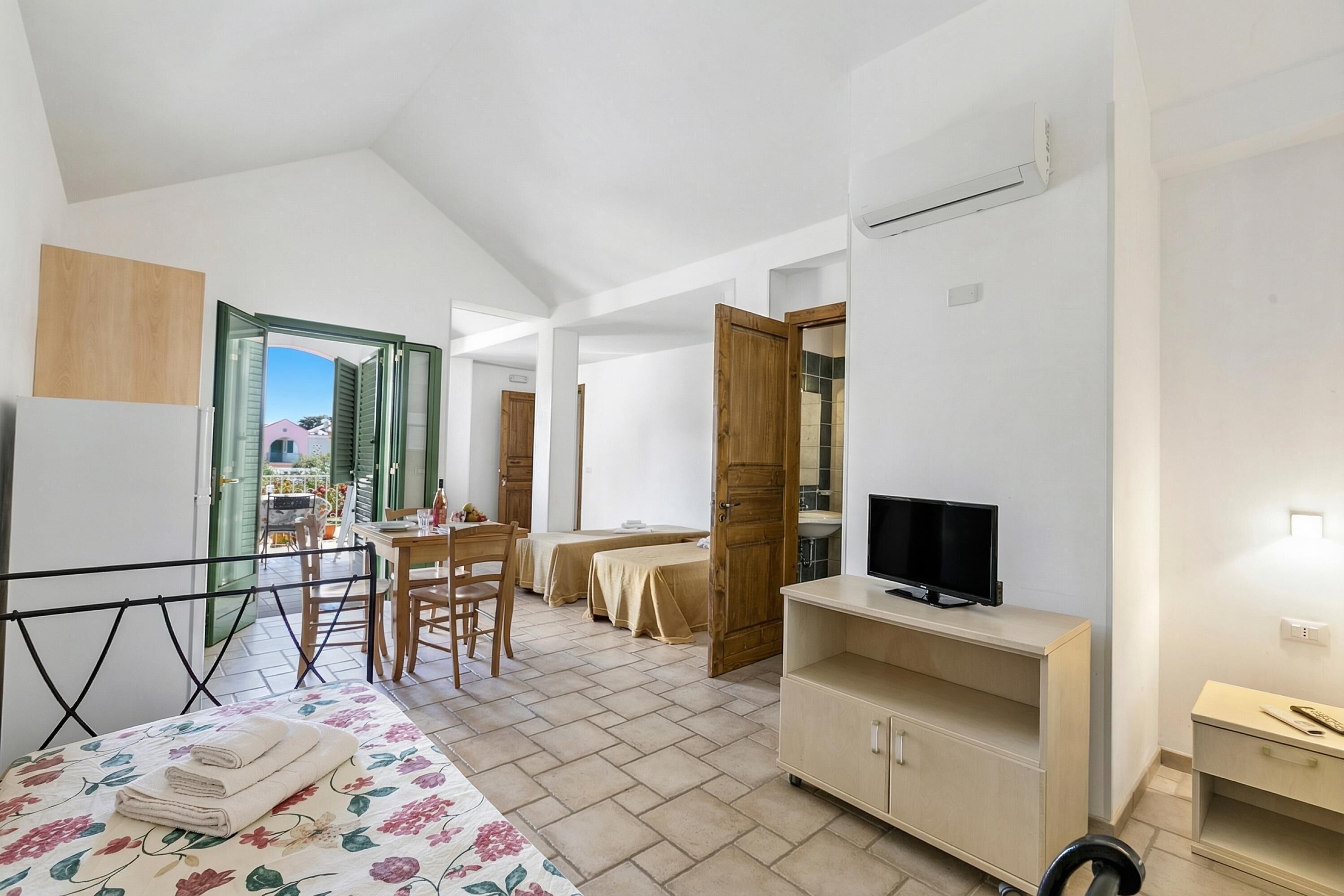 Une chambre à coucher comprenant un lit, une télévision, un bureau et un coin repas.