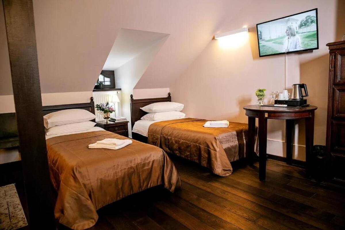 A hotel room with two beds, a television, a small table with a coffee maker, and a view of a building outside.