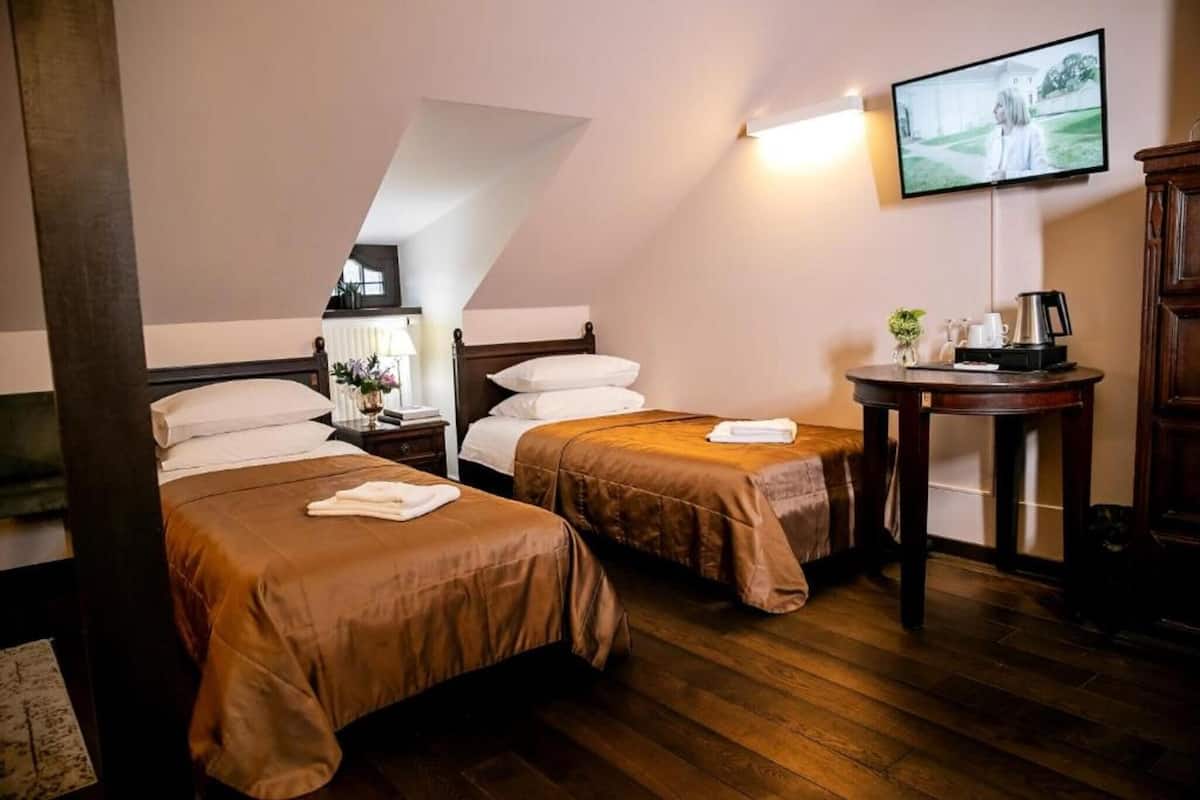 A hotel room with two beds, a television, a small table with a coffee maker, and a view of a building outside.