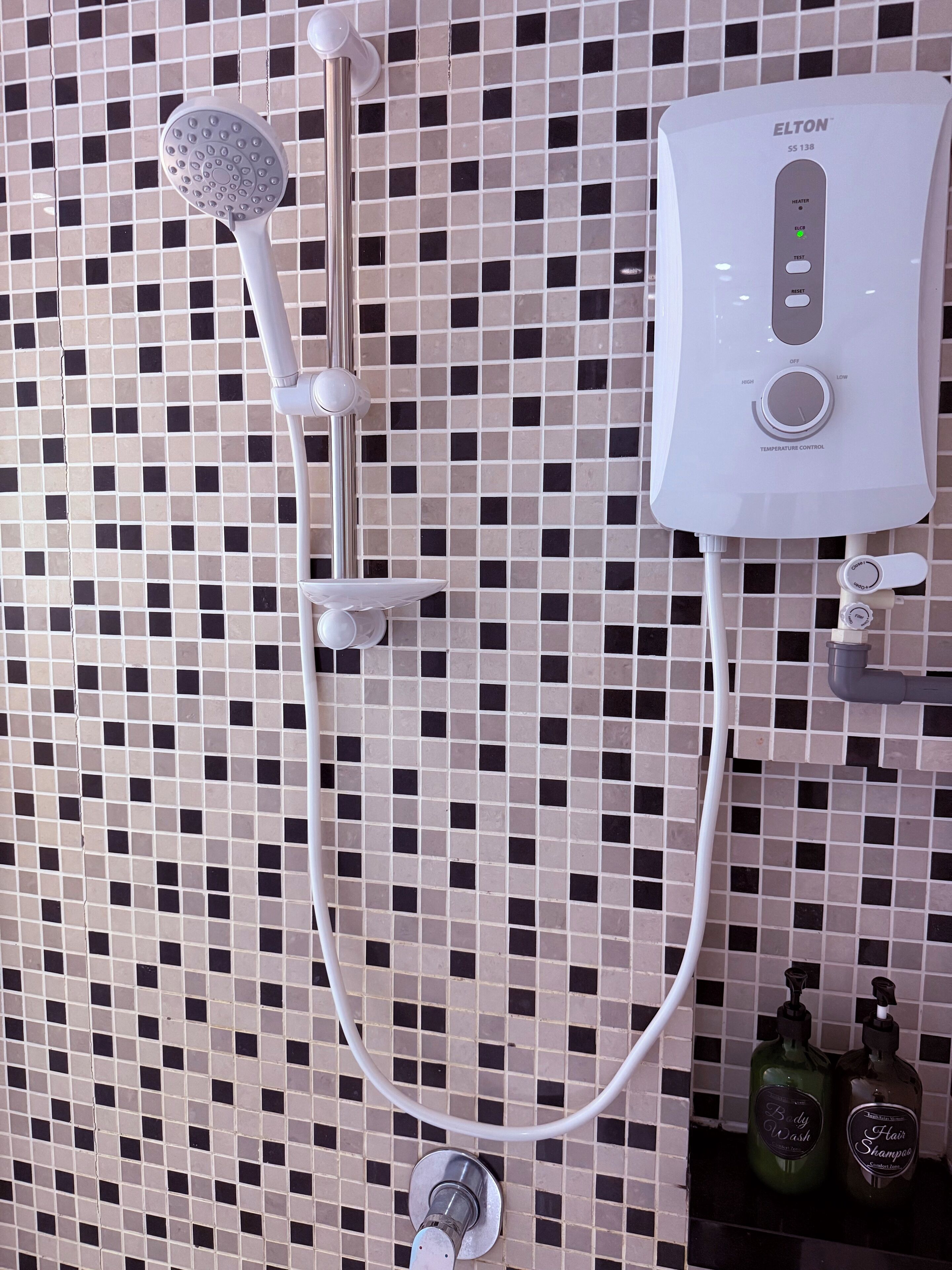 A bathroom with a shower, a control panel, and two bottles of shampoo and body wash.