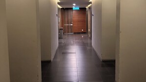 Een hal met een bord waarop 'KELUARAH' staat, leidend naar een kamer met een houten deur.
