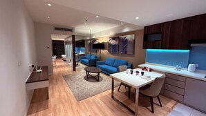 Een moderne woonkamer met een blauwe bank, een eettafel met stoelen en een keuken met een blauw aanrecht.