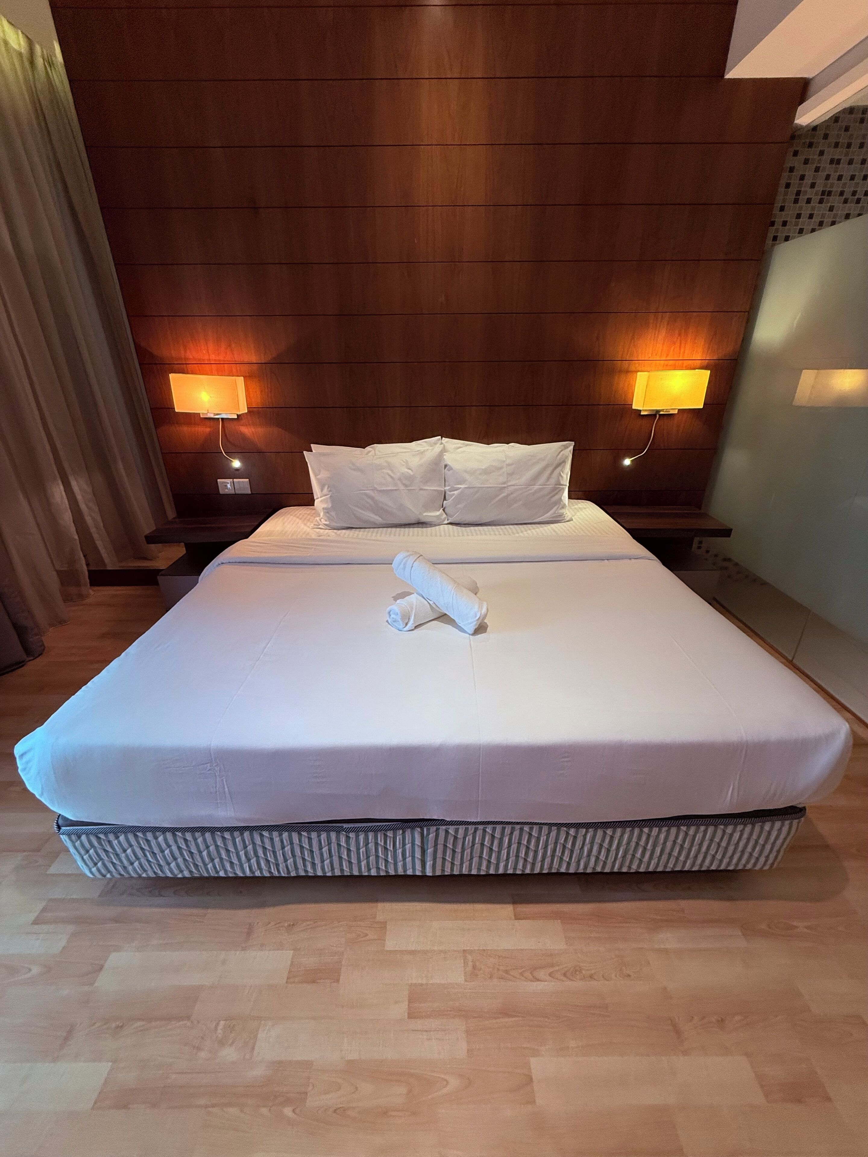 Une chambre d’hôtel avec un grand lit, deux lampes de chevet et une tête de lit en bois.