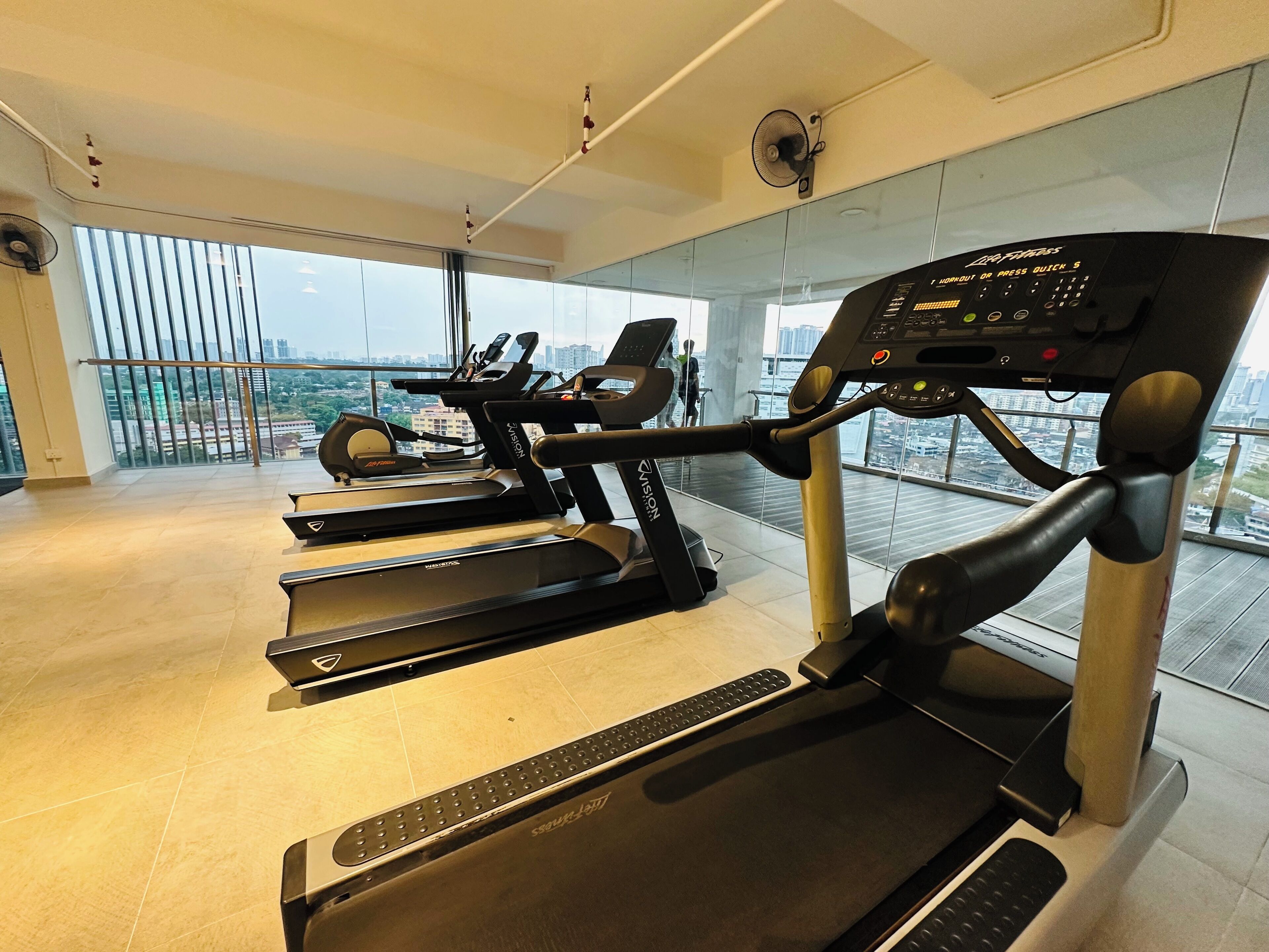 A gym with treadmills, a rowing machine, and a fan.