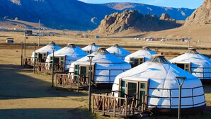 Yurts arranged in a row with wooden walkways, set against a mountainous backdrop. - Khumug Tour Resort (Ulaanbaatar)